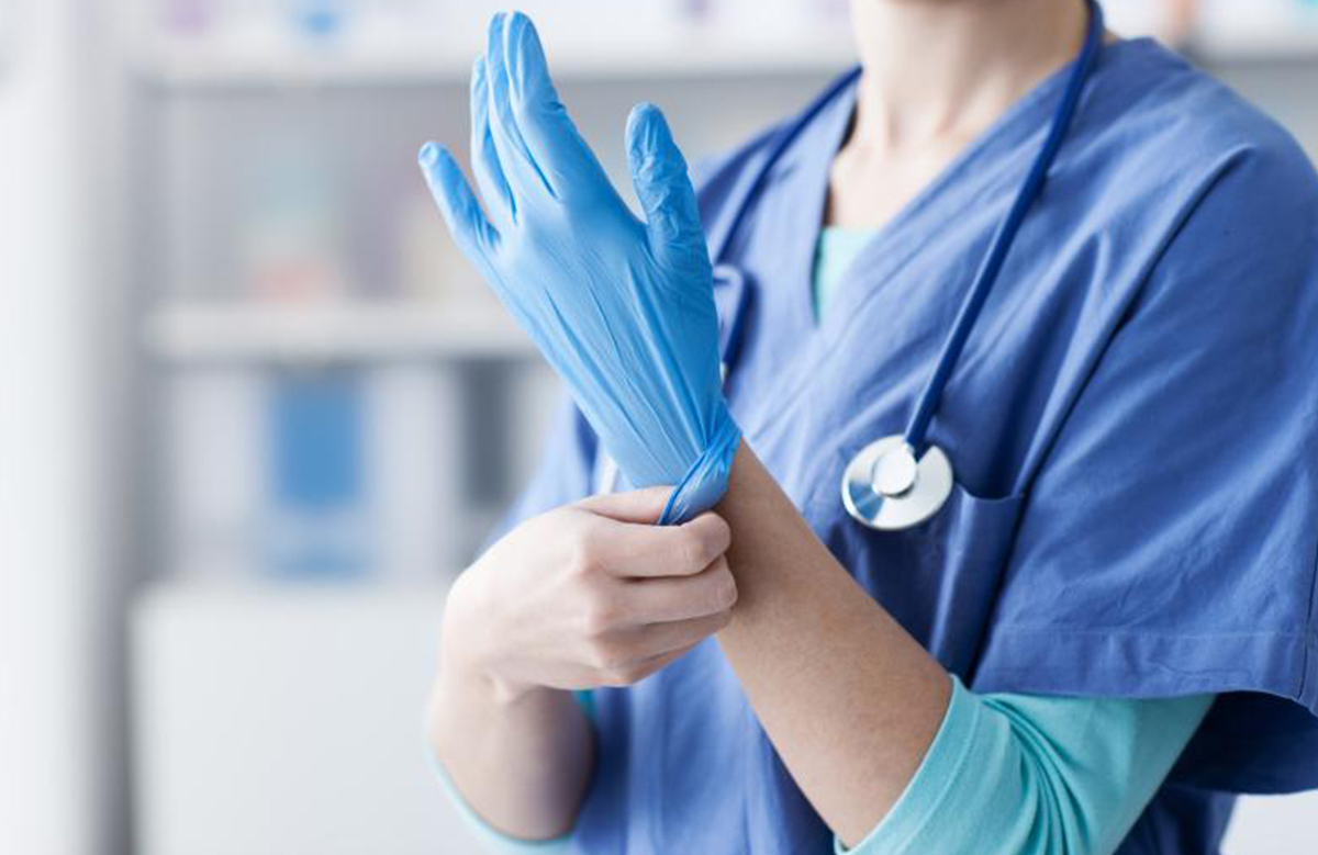 healthcare professional in scrubs putting on gloves